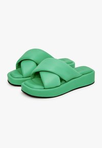Groene slidesandalen met een zachte, gevoerde bovenkant met een gedraaide indeling. Dikkere zool met een gladde afwerking en zwarte rubberen onderzijde voor grip.