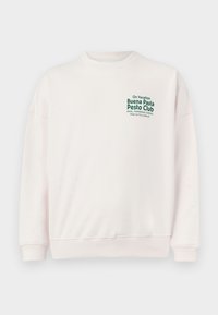 Lichtroze sweatshirt met lange mouwen, ronde hals en geribde boorden. Bevat groene tekst: "Op Vakantie, Buena Pasta Pesto Club."