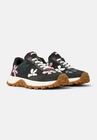 Black sneakers with a textured canvas upper, floral patterns in pink and green, white laces, and a rubber outsole with grip.