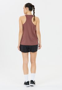 Bordeaux gestreept tanktop met een racerback-ontwerp gecombineerd met zwarte shorts. Model draagt witte crew-sokken en zwarte sport schoenen.