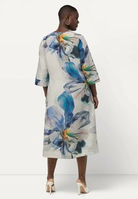 Vestido maxi con estampado de flores y mangas tres cuartos en una tela suave y ligera, que presenta diseños florales en azul y amarillo.