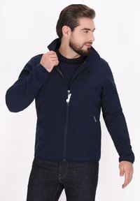 Tamsiai mėlyna zip-up striukė su aukštu apykakle, ilgomis rankovėmis ir šoniniu užtrauktuku. Pasižymi lygiu paviršiumi ir reguliuojamu raišteliu.