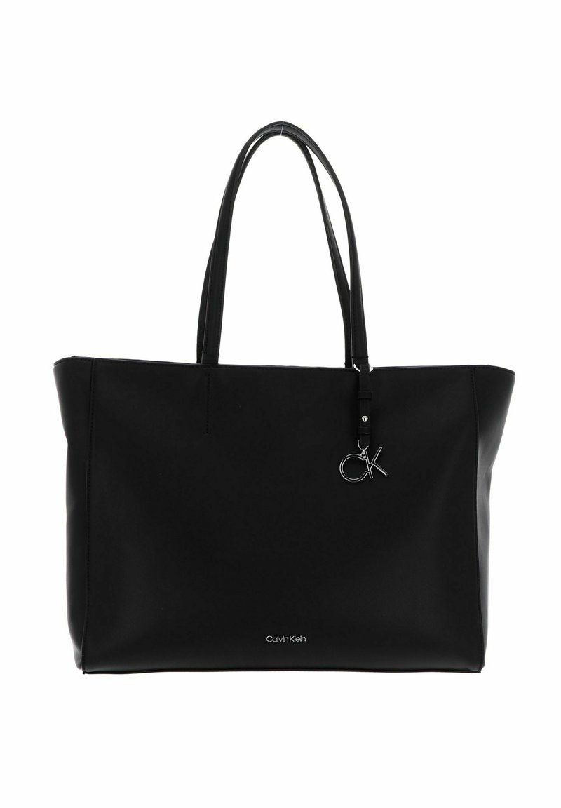 Sac cabas noir Calvin Klein avec deux poignées, design minimaliste et petit pendentif logo argenté "ck" suspendu près du bord supérieur.