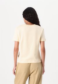 Crème-kleurig katoenen T-shirt met een ronde hals en korte mouwen, met een relaxte pasvorm en zichtbare naden op de achterkant.