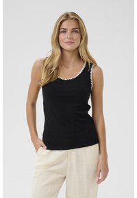 Mustmust värviline tank top valge lainelise äärisega kaeluses. Kehasse sobiv lõige, koos heledad beežist lina pükstega.