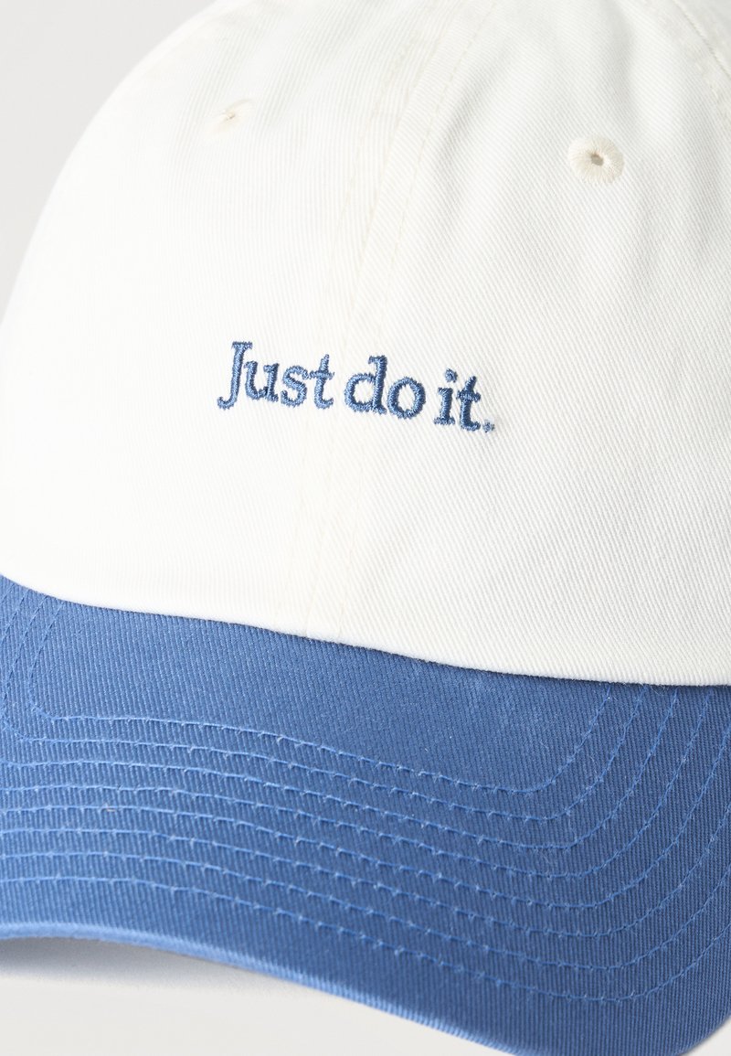Weiße und blaue Baseballkappe mit dem bestickten Text „Just do it.“ auf dem Frontpanel.