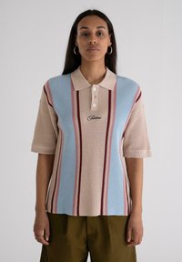 Polo shirt in beige, blue, and burgundy stripes with a textured knit fabric, short sleeves, and a buttoned collar. Black logo on front.