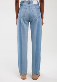 Lichtblauwe denim jeans met een rechte pijp, voorzien van een kleurblokontwerp en twee achterzakken. Subtiele textuurafwerking.