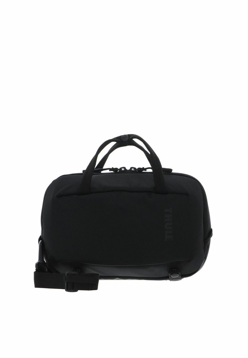 Sac de transport noir compact Thule avec double poignées, compartiment principal zippé et bandoulière ajustable.