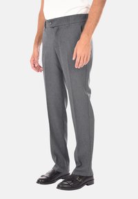Pantaloni grigi in tessuto strutturato, con taglio dritto, dotati di chiusura a bottone e tasche laterali, indossati con scarpe nere.
