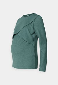 Bluzka ciążowa w kolorze teal, z warstwowym przodem, długimi rękawami, miękką fakturą i zaokrąglonym dołem dla większego komfortu w czasie ciąży.