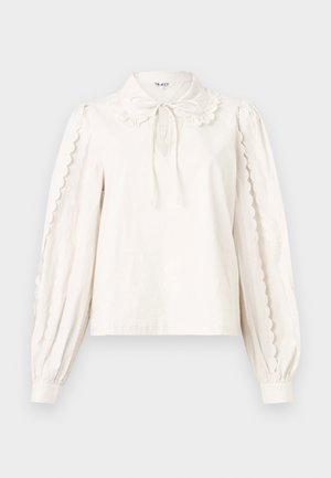 Blusa blanca de manga larga con bordes festoneados en las mangas, un cuello tipo Peter Pan con un lazo atado y puños abotonados.