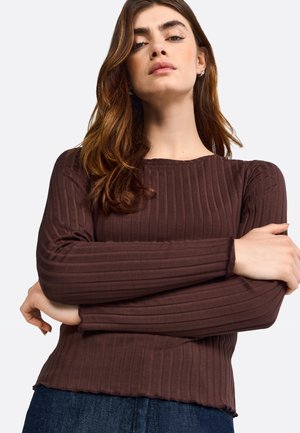 Top marrone a maniche lunghe con coste, colletto rotondo e orlo scallopato. Il tessuto ha una consistenza morbida, un design aderente e una leggera elasticità.