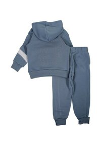 Ensemble pour enfant composé d'un sweat à capuche bleu et d'un pantalon assorti avec une bande blanche sur la manche gauche, présenté à plat sur un fond blanc.