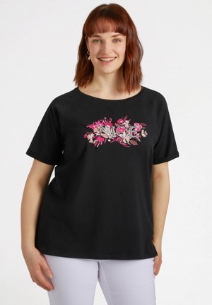 Camiseta de algodón negra con escote redondo y mangas cortas, que presenta un intrincado bordado floral en tonos rosas y neutros a lo largo del pecho.