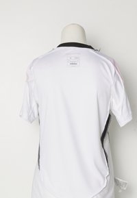 Bijela atletska majica kratkih rukava, okrugli crni ovratnik i crni bočni naglasci. Sadrži Adidas logo i oznaku za njegu na leđima.