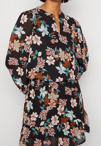 Abito nero con stampa floreale vivace in rosa, blu e marrone, con scollo a V, maniche lunghe e gonna a balze.