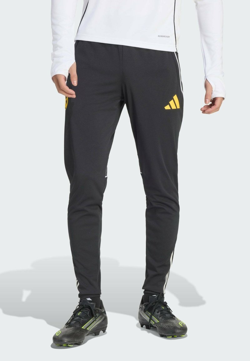 Svarta träningsbyxor i lätt tyg med gula Adidas-logotypen och vita sidoskär, med smal passform och elastisk midja.