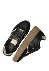 Baskets noires avec une semelle en caoutchouc texturé, présentant des accents beige clair, des lacets tressés et un talon à motifs. Matériaux en cuir lisse et en daim.