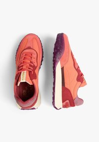 Zapatillas de deporte de color rojo brillante y rosa, fabricadas con materiales de ante texturizado y malla, que cuentan con una suela morada con diseño estampado y un sistema de cordones.