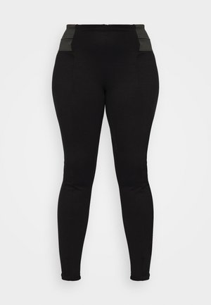 Musta korkeavyötäröinen legginsit, joissa on teksturoidut, joustavat vyötärönauhat ja suora istuvuus. Vyötärönauhassa on kulmikkaita harmaita korostuksia.