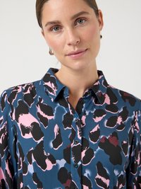 Mėlyna marškinėliai su rožine, juoda ir purpurine abstrakčia raštais, su sagomis, klasikiniu apykaklė ir minkšta tekstūra.