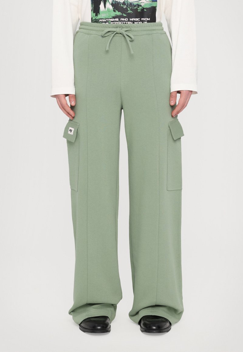 Green wide-leg sweatpants made of soft fabric, featuring a drawstring waistband and side cargo pockets with flap closures.