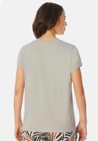 Light gray short-sleeve T-shirt with a round neckline and soft texture, paired with patterned pants featuring orange and navy accents.