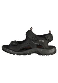 Svart utendørs sandal med syntetisk overdel, borrelåsstropper, perforeringer og robust såle for godt grep. Lett og pustende design.