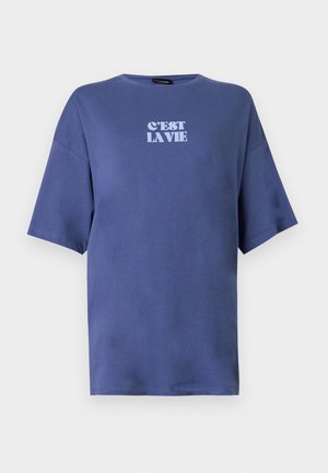 T-shirt bleu oversize à manches courtes avec col rond et texte blanc "C'EST LA VIE" centré sur la poitrine.