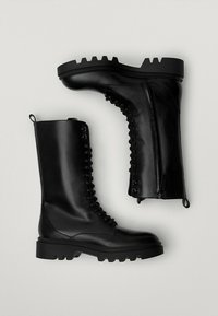 Czarne skórzane buty wojskowe z grubą, twardą podeszwą, sznurowanym przodem i bocznym zamkiem. Posiadają teksturowane przeszycia po bokach.