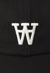 Zwarte pet van textuurstof met een geborduurd wit "W" logo op de voorkant. Heeft een gebogen klep en een gestructureerd ontwerp.