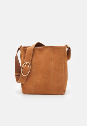 Borsa in suede color cammello con forma piatta e rettangolare, caratterizzata da una larga tracolla in pelle e una grande fibbia circolare in metallo.