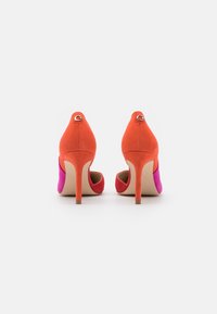 Chaussures à talons hauts avec un design bicolore en daim orange et rose. Dotées d'un bout pointu et d'un petit logo au talon.
