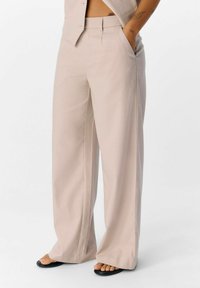 Helle beige, weit geschnittene Hose mit vertikalen Streifen, hoher Taille, seitlichen Taschen und einer glatten Stofftextur.