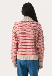 Röd och krämfärgad mönstrad tröja med hög hals, ribbade ärm- och fållkanter, med en geometrisk design över ryggen.