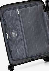 Black rolling suitcase interior features gray fabric with subtle branding, zippered compartments, and a mesh pocket for organization.