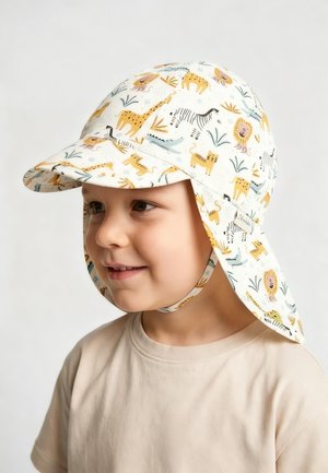 Child smiling sideways wearing a white sun hat with neck flap featuring yellow and black safari animal prints.