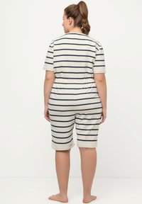Stribet romper i creme og marineblå, korte ærmer, elastisk talje, knæ-lange shorts, blødt bomuldsmateriale, afslappet design.