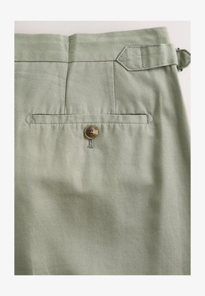 Zelene bombažne hlače z zadnjim žepom na gumb in ravnim pasom. Tkanina ima gladek, teksturiran zaključek.