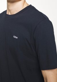 Marineblå bomulds T-shirt med rund hals og korte ærmer, med et lille broderet logo på venstre bryst.