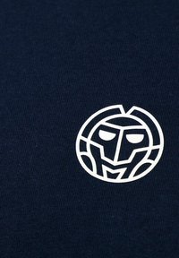 Marineblaues Material mit einem weißen, kreisförmigen Grafik eines Gesichts, das geometrische Linien und markante Gesichtszüge zeigt. Texturierte Strickoberfläche.