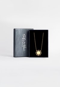 Collana d'oro con pendente circolare caratterizzato da un design geometrico aperto, esposta in una scatola gioielli grigia con interno in velluto nero.