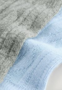 Two fabric swatches: one light gray textured knit with a fuzzy finish, and one soft blue knit with a smooth surface and even pattern.