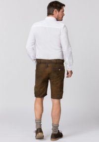 Bruine leren shorts met een gladde textuur, voorzien van een achterzak en riemlussen, gecombineerd met grijze knielange sokken en bruine schoenen.