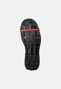 Suela de zapato de goma negra con un patrón de banda profunda, que cuenta con una banda de acento roja cerca del talón, y marcada con "CAMPER" y tamaño "38".