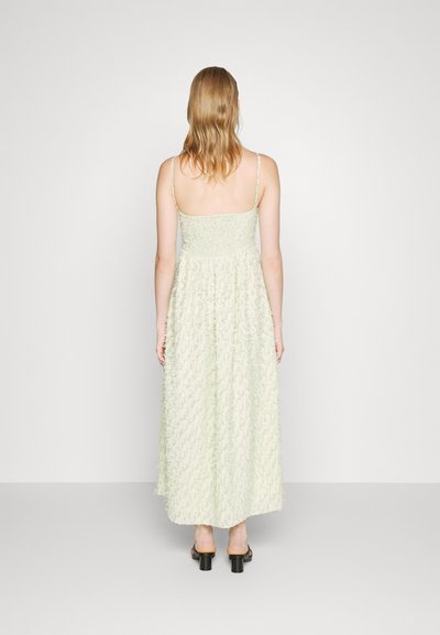 Vestido maxi em verde claro, com um design floral texturizado, alças finas ajustáveis e um corpete franzido. Silhueta fluida.