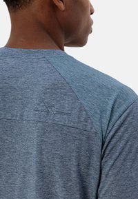Maglietta sportiva da uomo con un design blu tono su tono, maniche corte e un logo geometrico sulla schiena, caratterizzata da una texture liscia.