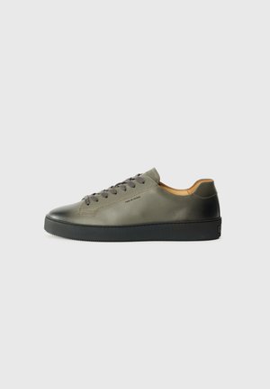 Sneakers in olive green leather with black rubber sole. Features round toe, tonal laces, and minimalistic design. Inside lined with tan material.