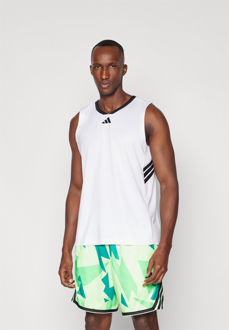 Weißes ärmelloses Sportshirt mit schwarzen Akzenten, kombiniert mit grünem Shorts im geometrischen Muster. Das Material wirkt leicht und atmungsaktiv.